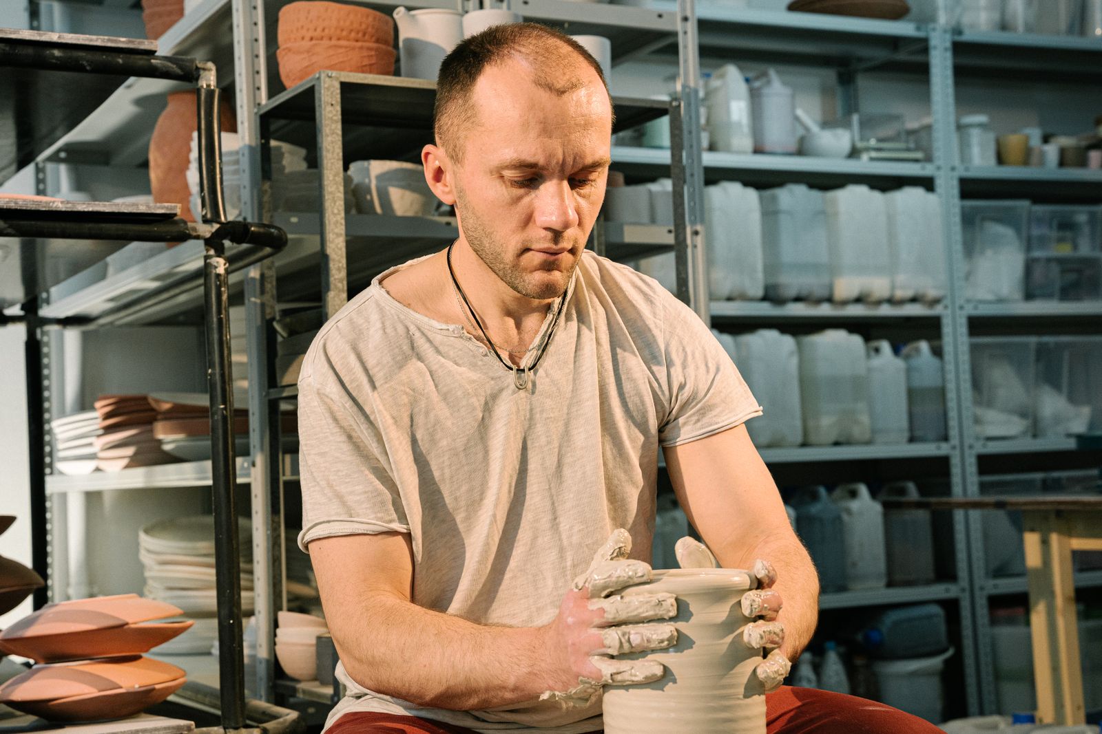A skilled artisan shaping clay into pottery in a light-filled studio.